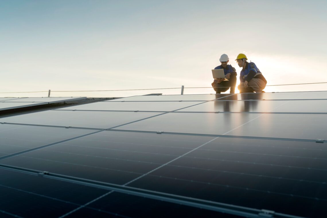 Zwei Personen stehen auf einem Dach wo eine Solaranlage installiert ist