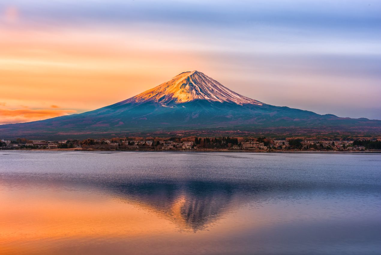 Der Mount Fuji im goldenen Sonnenaufgang spiegelt sich im Wasser, ein Symbol für die Schönheit von Bergabenteuern wie der Besteigung Kilimandscharo.