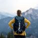 Eine Frau mit Rucksack genießt die Aussicht auf eine beeindruckende Bergkulisse, perfekt zur Vorbereitung auf die Besteigung Kilimandscharo.