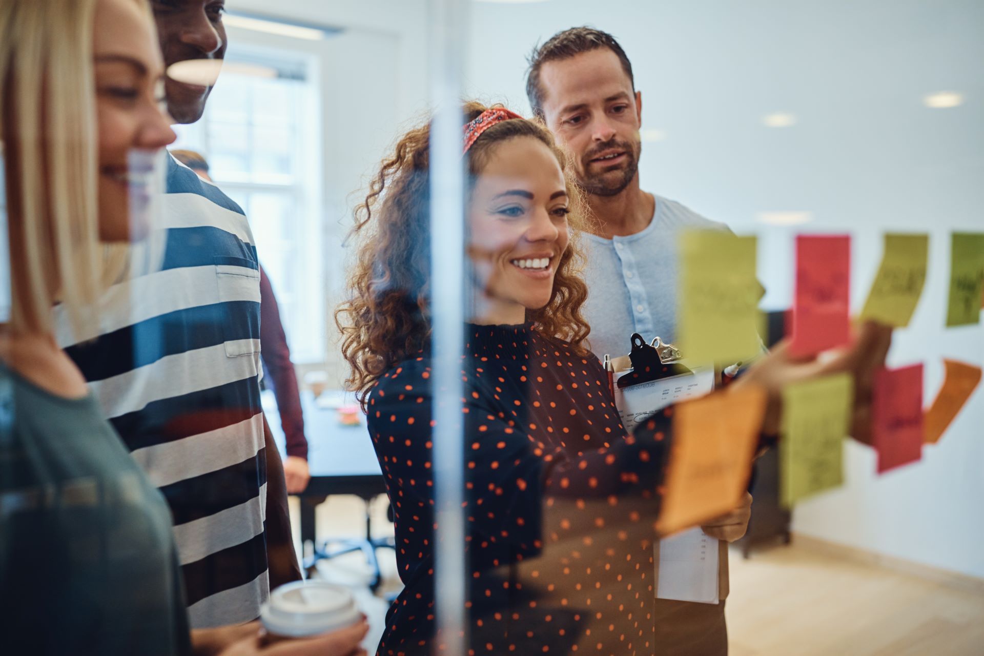 Marketing-Team bei der Strategieplanung – Eine Gruppe von Kollegen brainstormt an einer Glaswand mit bunten Haftnotizen.  